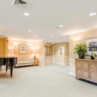A well-lit lobby area featuring a piano, comfortable seating, and elegant decor.