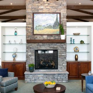 A cozy living room featuring a stone fireplace, built-in shelves, and modern decor with comfortable seating.