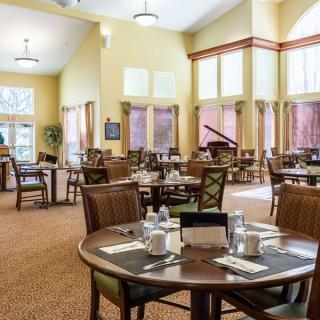 A well-lit dining room with neatly arranged tables and chairs.