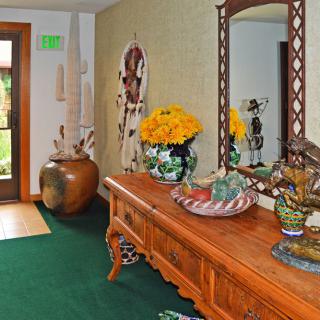 A warmly decorated entryway with a wooden table, mirror, and vibrant floral arrangement.