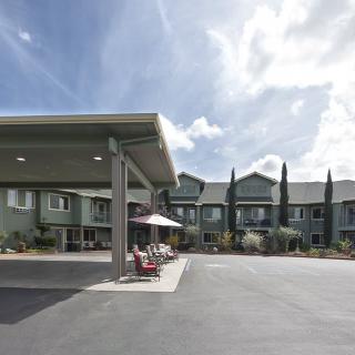 A modern hotel building with a spacious parking area under a partly cloudy sky.