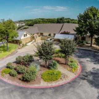 Aerial view of a residential building surrounded by landscaped gardens and trees.
