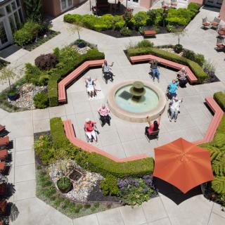 Aerial view of a courtyard with a central fountain, surrounded by benches and lush greenery.