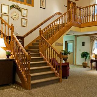 A cozy interior featuring a wooden staircase with carpeted steps, surrounded by warm lighting and decorative furnishings.