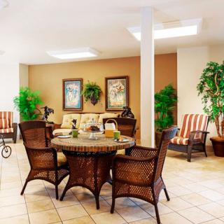 A cozy living room with wicker chairs and a table, decorated with plants and artwork.