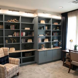 A cozy corner of a modern library featuring bookshelves filled with various books and decorative items.