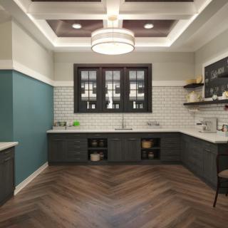 A modern kitchen with dark cabinets, wood flooring, and a stylish ceiling light.
