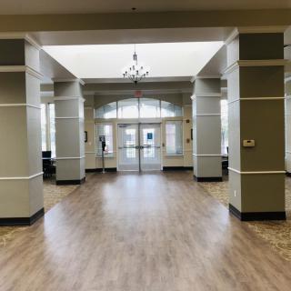 Spacious lobby with wooden flooring and large windows.