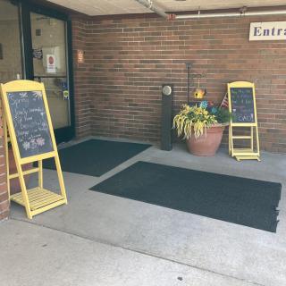 Outdoor entrance with chalkboard signs and flowers.
