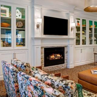 A cozy living room featuring a fireplace, television, and floral-patterned chairs.