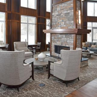 A modern lobby with a cozy seating area around a central fireplace.