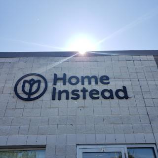 The exterior of a Home Instead location, with the sun shining above.