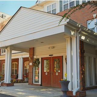 The image shows the entrance of a brick building with white columns and double doors.