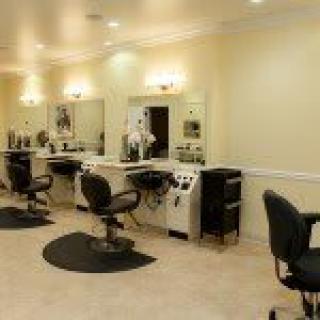 A well-lit hair salon interior with multiple styling stations and chairs.