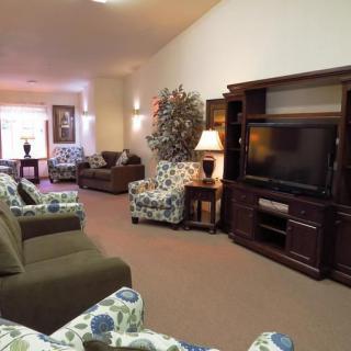 A cozy living room featuring a television, several couches, and decorative elements.