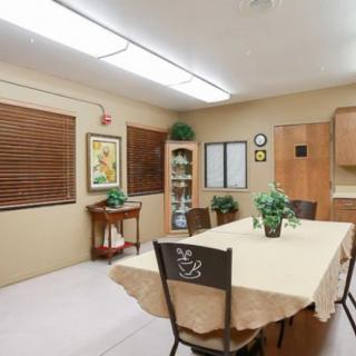 Cozy dining room with a table set for four, featuring warm lighting and decorative plants.