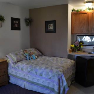 A cozy bedroom with a neatly made bed and small kitchenette area.