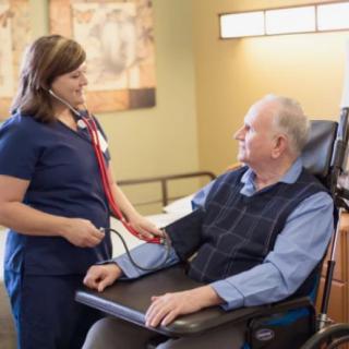 A nurse checks the blood pressure of an elderly patient in a healthcare setting.