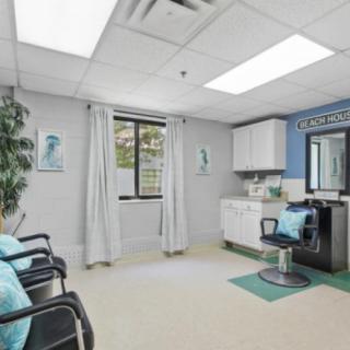 A modern salon interior featuring a barber chair, mirrors, and seating area with decorative plants.