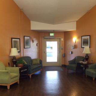 A cozy waiting room with chairs, lamps, and framed pictures on the walls.