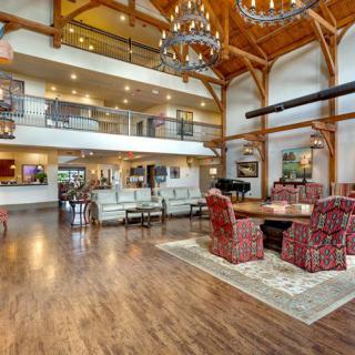 A spacious and modern lobby with wooden beams, chandeliers, and a comfortable seating area.