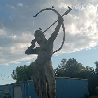 A striking statue of an archer poised with a bow, set against a beautiful cloudy sky.