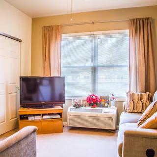 A cozy living room featuring a sofa, television, and large window with curtains.