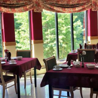 A quaint dining area featuring elegantly set tables and large windows that invite natural light.