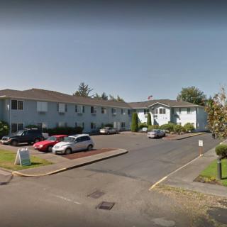 A residential apartment building with a parking lot and several parked cars.