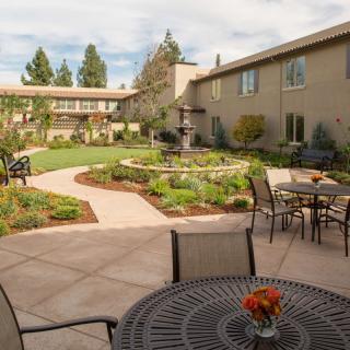 A beautifully landscaped courtyard with outdoor seating and a winding pathway surrounded by greenery.