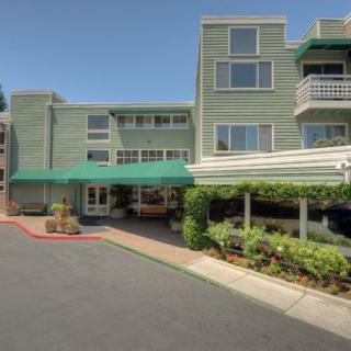 A green exterior building with a hotel entrance and landscaped surroundings.