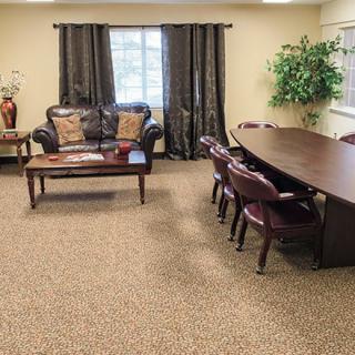A cozy conference room with a meeting table, chairs, sofa, and decorative plants.