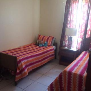 A cozy bedroom with two beds featuring bright, striped bedding.