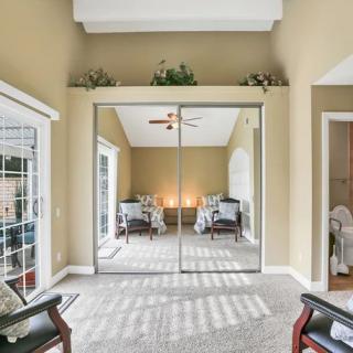 A spacious bedroom with mirrored sliding closet doors and ample natural light.
