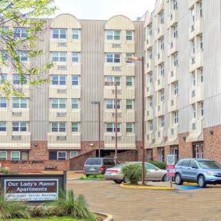 A view of a residential building with a parking lot and several parked cars.