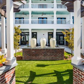 A hotel courtyard featuring a fountain and landscaped garden, surrounded by a building with balconies.