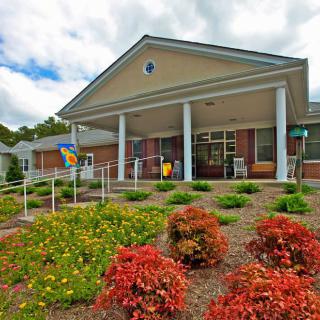 A building with a landscaped garden and columns at the entrance.