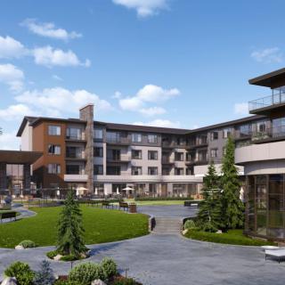 A modern residential building with landscaped gardens under a clear blue sky.