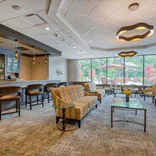 A spacious and modern lobby with comfortable seating, a bar area, and large windows providing natural light.