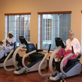 Seniors engaging in physical activity using exercise bikes in a bright and welcoming gym environment.