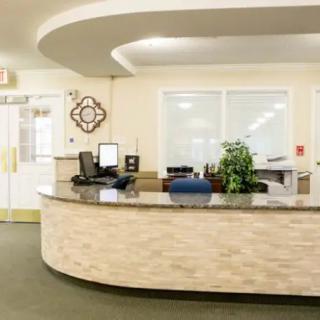 A modern reception desk with computer equipment and a potted plant.