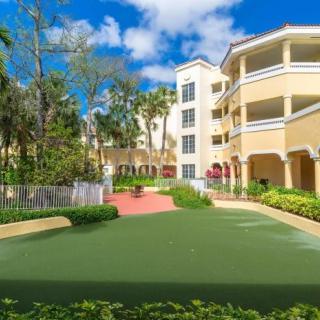 A sunny view of a residential building complex with landscaped gardens.