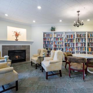 A cozy library room with bookshelves, a fireplace, and comfortable seating.