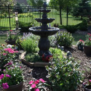 A beautiful garden with a central fountain surrounded by colorful flowers.