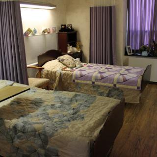 A cozy bedroom featuring two beds with patterned bedding and purple curtains.