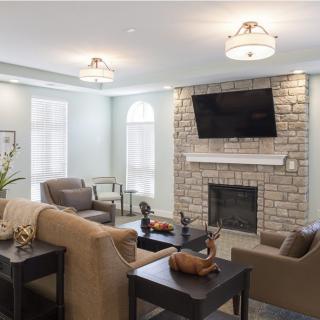 A modern living room with a cozy seating area and a fireplace beneath a wall-mounted TV.