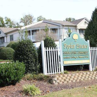 Entrance to an apartment complex with a decorative sign and well-maintained landscaping.