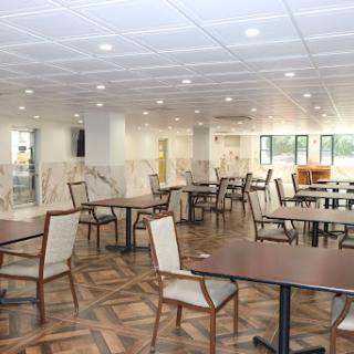 A spacious and modern dining area featuring tables and chairs, illuminated by bright overhead lights.