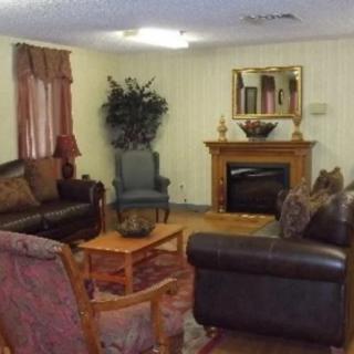 A cozy living room with sofas, chairs, a fireplace, and a mirror on the wall.