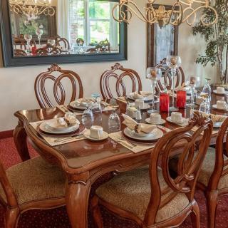 An elegantly set dining table with wooden chairs and a chandelier overhead.